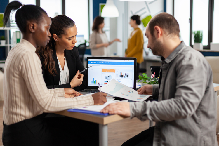Group of business people discussing stats over a laptop